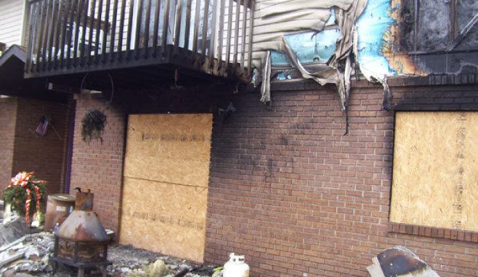Exterior of a residential house boarded up after severe fire damage