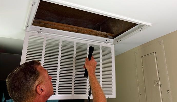 Technician inspecting a damaged HVAC duct system