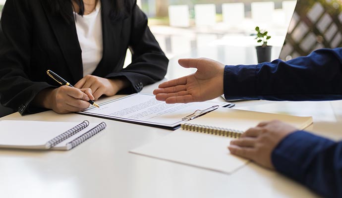 Two people reviewing and signing documents at a desk