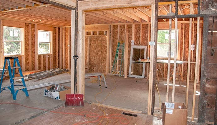 Interior view of a house under reconstruction with exposed wooden framing and construction materials