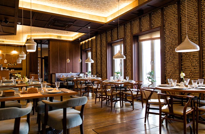An interior view of a clean restaurant with multiple wooden tables with set of plate and glass
