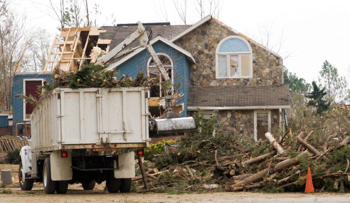 Cleanup truck clearing storm debris from disaster-damaged property