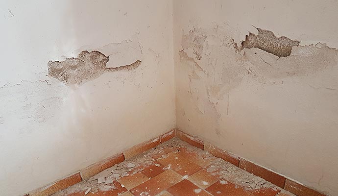 Structurally damaged interior wall with cracks and peeling paint