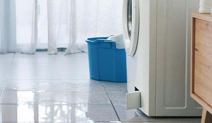 Water spreading across the floor from leaking washing machine
